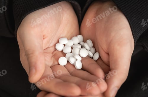 Preview: A lot of white pills in the hands of an adult man.