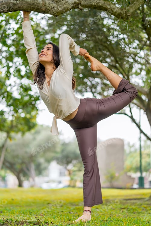 Preview: Young woman practicing yoga in urban park, balancing pose and healthy lifestyle