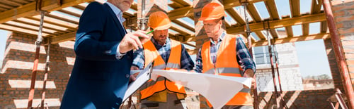 Preview: panoramic shot of businessman near builders holding blueprint
