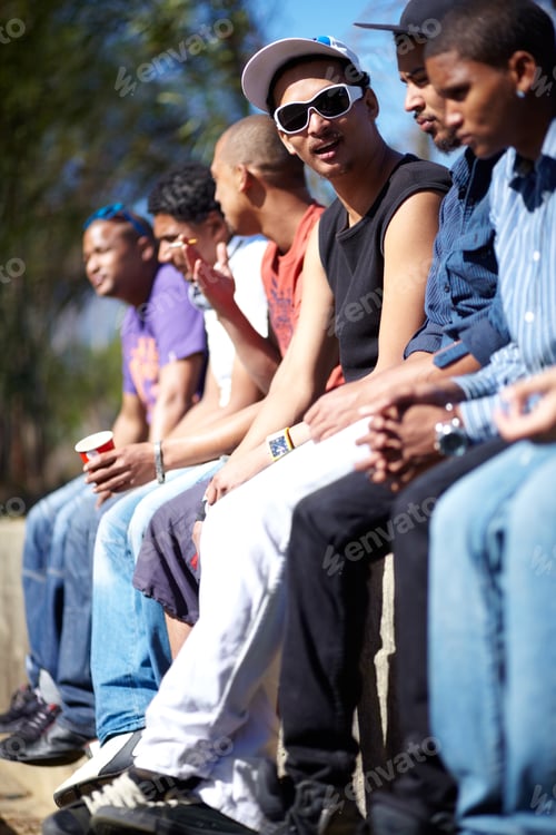 Preview: Just hanging out. Shot of a group of friends sitting on a wall together.