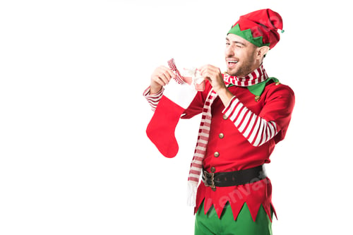 Preview: man in christmas elf costume winging and putting present in red christmas stocking isolated on white