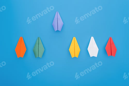 Preview: Flat lay with colorful paper planes on blue surface