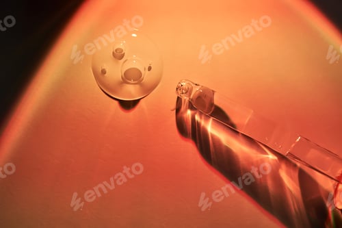 Preview: A dropper and a drop of sunscreen body serum in the orange sunset light.