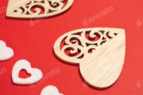 Preview: Close-up of wooden hearts and shiny white hearts on a red background