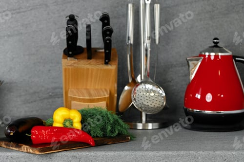 Preview: Kitchenware and cutting board with vegetables on countertop