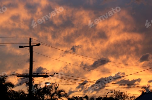 Preview: Telephone pole and electrical power lines against a stormy sunset sky