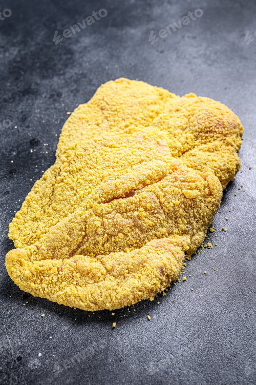 Preview: Raw Homemade Breaded German Weiner Schnitzel. Black background. Top view