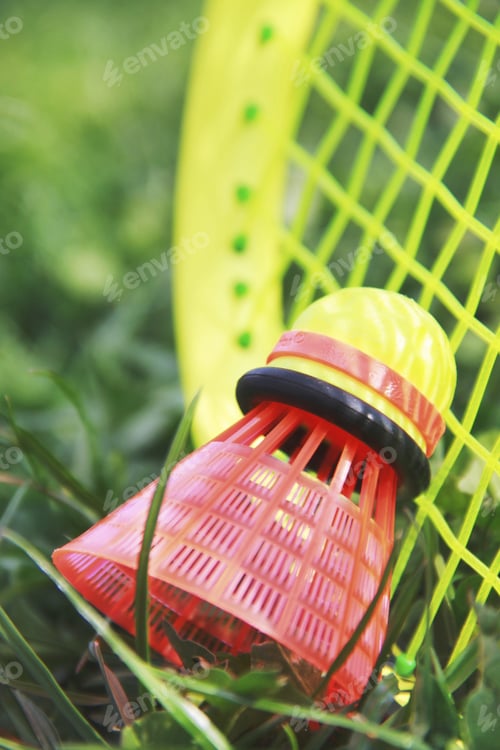 Preview: Close up badminton racket and shutllecock laying on the grass