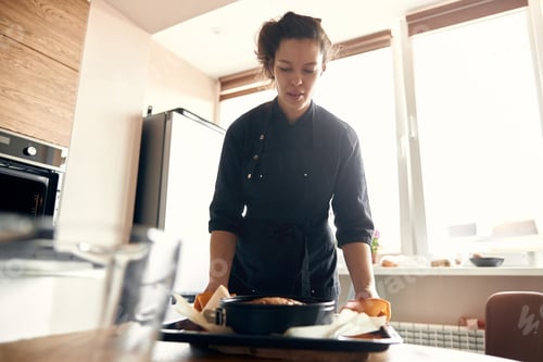 Preview: young professional female cook is preparing tasty cake at her light modern kitchen