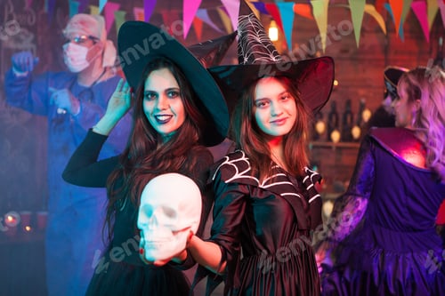 Preview: Sisters dressed up like witches at a halloween party holding a skull