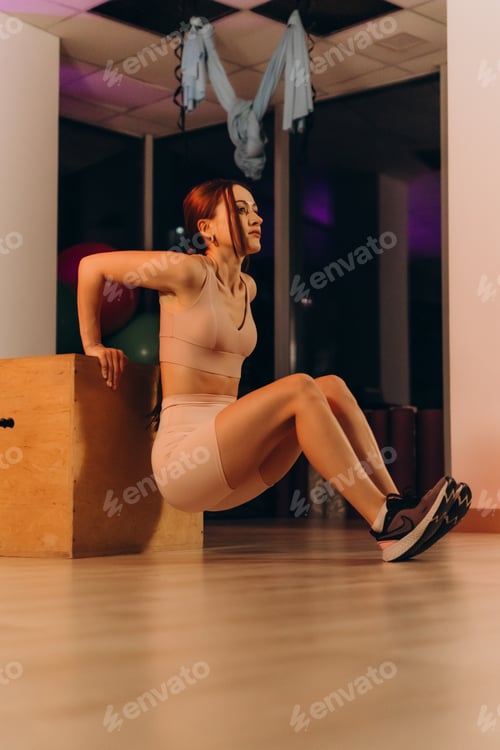 Preview: young sportswoman doing squats using bench in gym