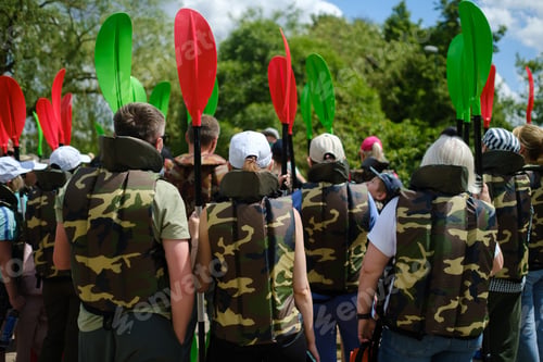 Preview: Group of individuals preparing for kayaking activity at a lake surrounded by greenery