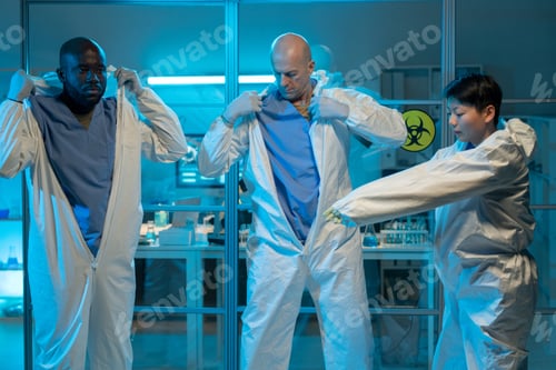 Preview: Three intercultural colleagues putting on protective coveralls