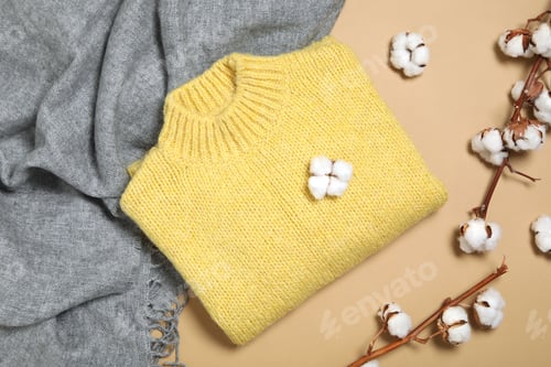 Preview: Warm sweater, scarf and cotton flowers on beige background, flat lay. Autumn season