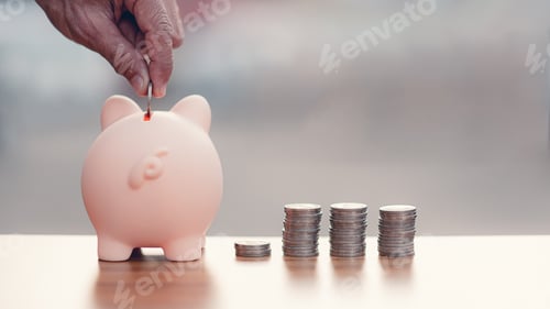 Preview: Hands holding coin put in the piggy bank with coins stacks on wood table