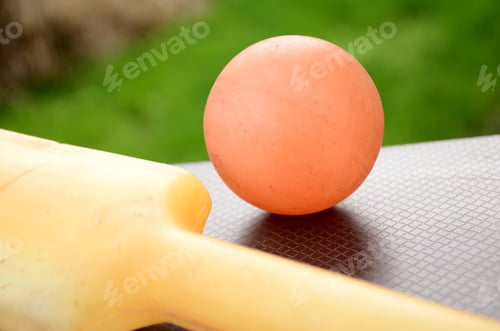 Preview: Closeup of the plastic cricket bat and an orange ball on the metallic surface