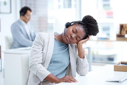 Preview: Dozing off during her shift. Shot of a young call centre agent sleeping at her desk in an office.