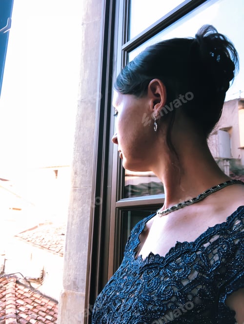 Preview: A portrait of a woman dressed up in formal evening gown looking out on from a hotel window
