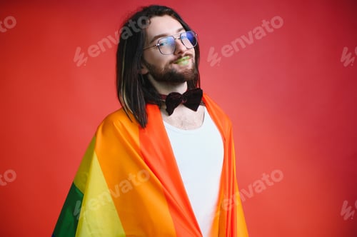 Preview: Gay man hold rainbow striped flag isolated on colored background studio portrait.
