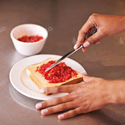 Preview: Fruity treat for breakfast. Cropped shot of a woman spreading fruity jam onto toast.