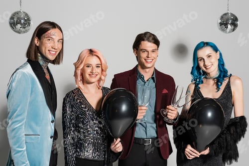 Preview: happy queer people with black balloons and champagne glasses looking at camera on grey background