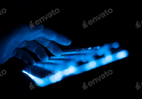 Preview: side view of fingers typing on illuminated RGB keyboard in the dark
