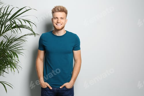 Preview: Young man wearing blank t-shirt on light background. Mockup for design
