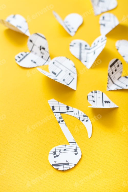 Preview: Musical notes, clef and hearts cut from paper with musical text on yellow background. Vertical view