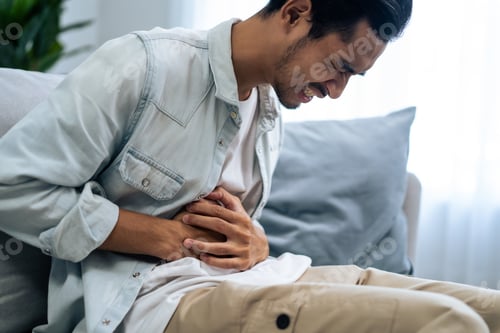 Preview: Asian attractive sick male suffer from hurt stomachache in living room.