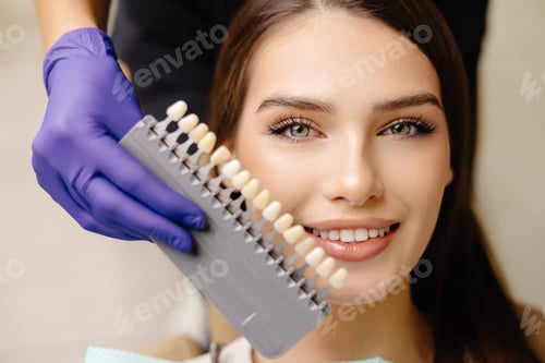 Preview: Dentist choosing teeth enamel shade color for female patient before whitening procedure
