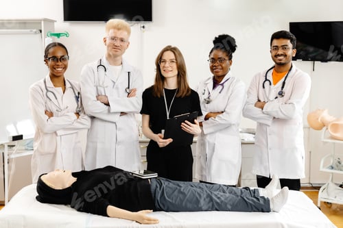 Preview: Group of doctors standing at the bed with mannequin at first aid training course