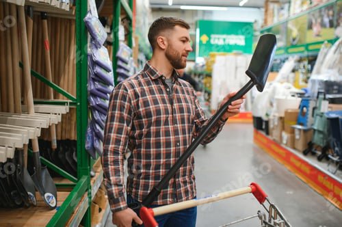 Preview: Portrait of a happy young man and customer buying a shovel while shopping at the hardware store