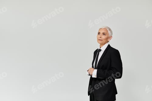 Preview: Elegant Mature Woman in Stylish Attire Poses Confidently Against a Minimalist Background