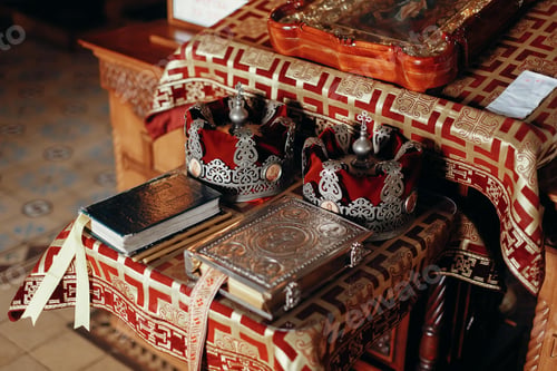 Preview: Golden bible, gospel, crowns and cross and icon on red and gold altar in church