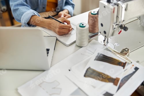 Preview: Talented African-American woman draws clothes model at workplace with modern sewing machine