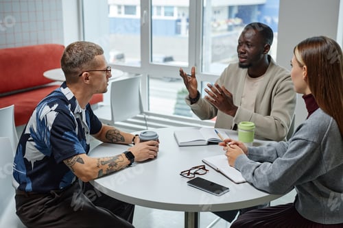 Preview: Businessman Collaborating with Colleagues Discussing Business Plan at Cafe Table