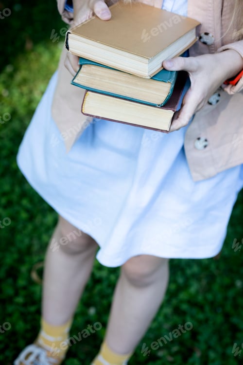 Preview: girl holding a stack of books in her hands