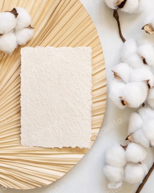 Preview: Blank handmade paper card on dried palm leaf with cotton flowers top view, wedding mockup