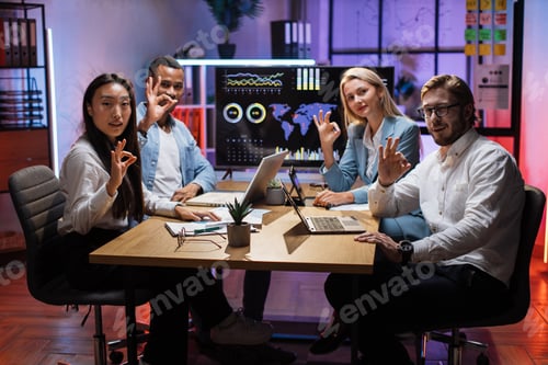 Preview: Four multi ethnic office workers showing okay sign on camera