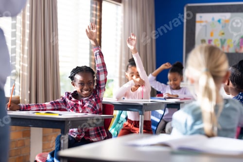 Preview: In school, diverse students raising hands in classroom, actively participating in lesson