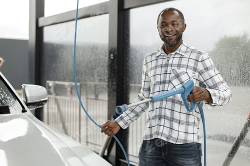 Preview: Middle aged black man cleaning his car outside in the car wash