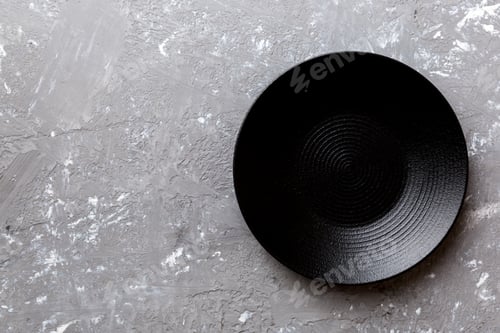 Preview: Top view of black plate on cement background. Empty space for your design