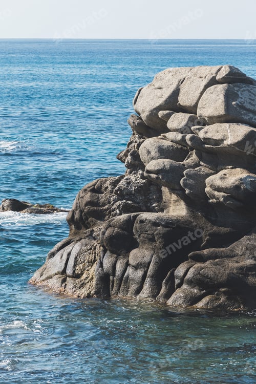 Preview: Wild rocky beach coastline and the sea, wave splashes on rock in sea shore, calm sea. Breaking waves