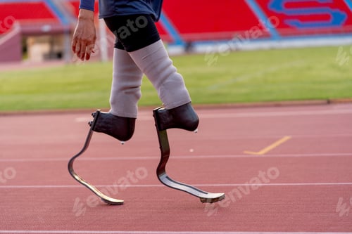 Preview: Side view of sport man athlete prosthesis legs stand and warm up legs on track in the stadium.