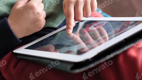 Preview: Cheerful little boy smiling while sitting on couch and using tablet at home. Modern kid and