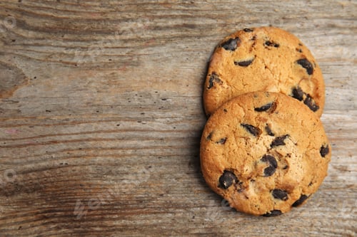 Preview: Delicious chocolate chip cookies on wooden table, flat lay. Space for text