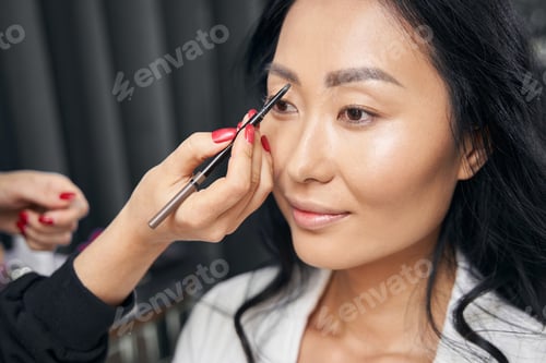 Preview: Young elegant business lady receiving professional make up in beauty space
