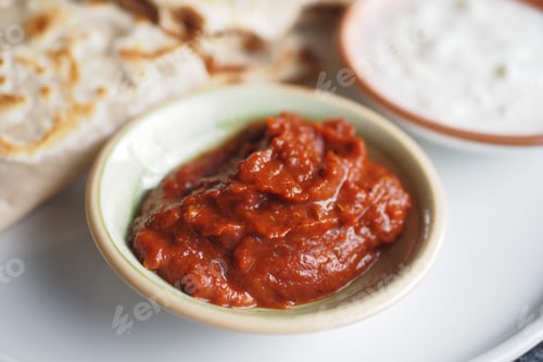 Preview: Delicious and spicy red chili sauce served alongside fresh flatbread and a creamy yogurt dip