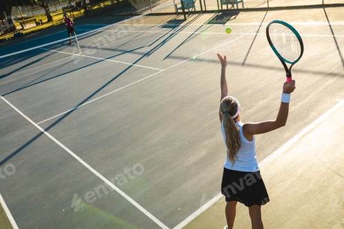 Preview: High angle view of young caucasian female tennis player serving during game at court