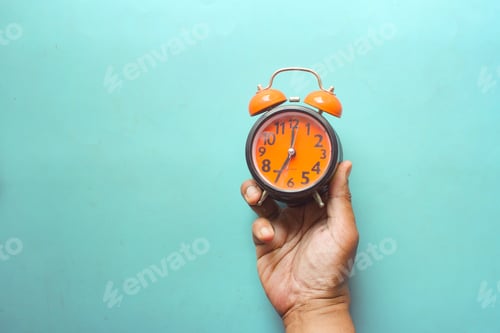 Preview: man hand holding alarm clock color background ,